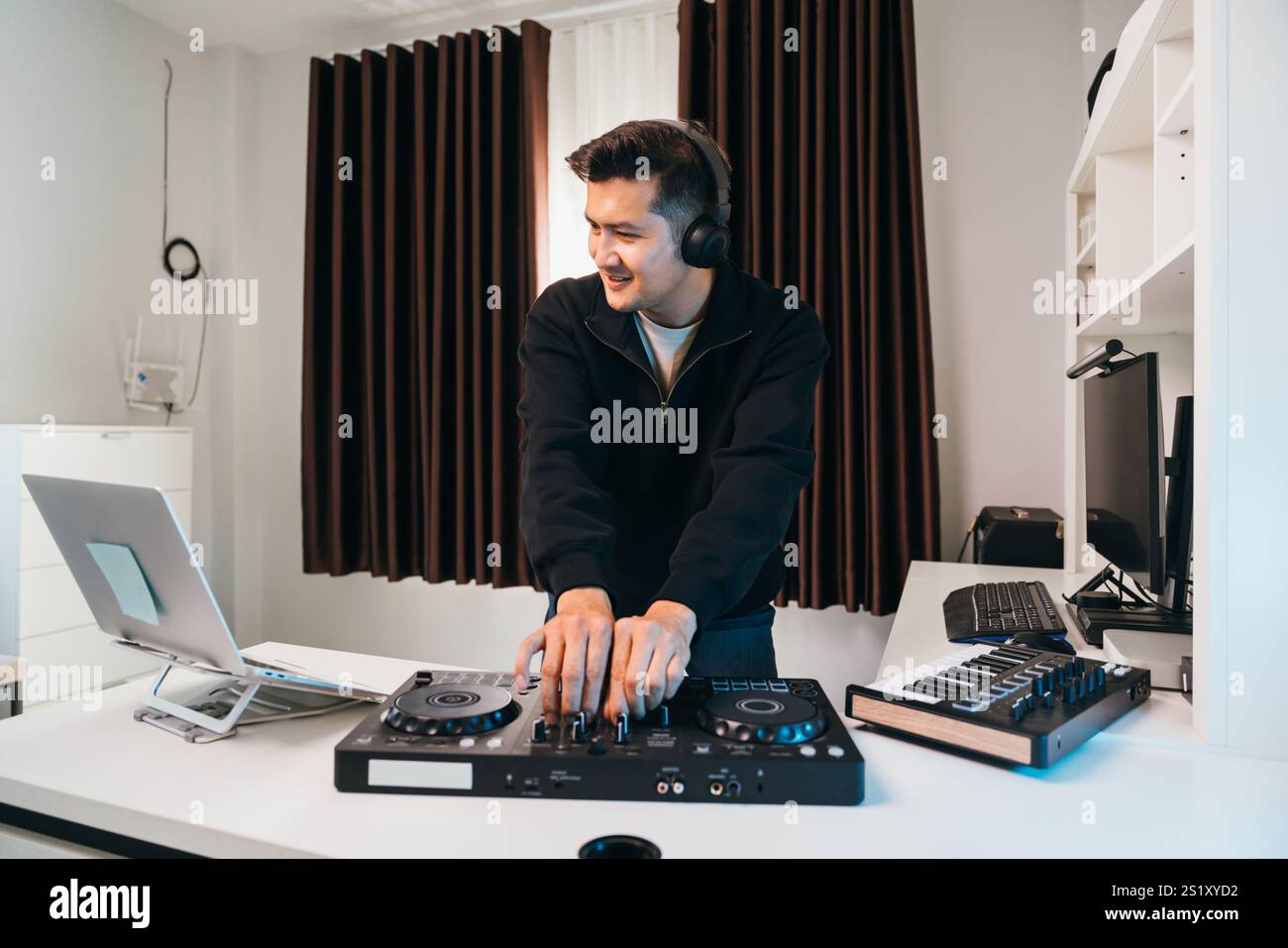 Un giovane DJ che gira le tracce su una futuristica console mixer a casa. Foto Stock