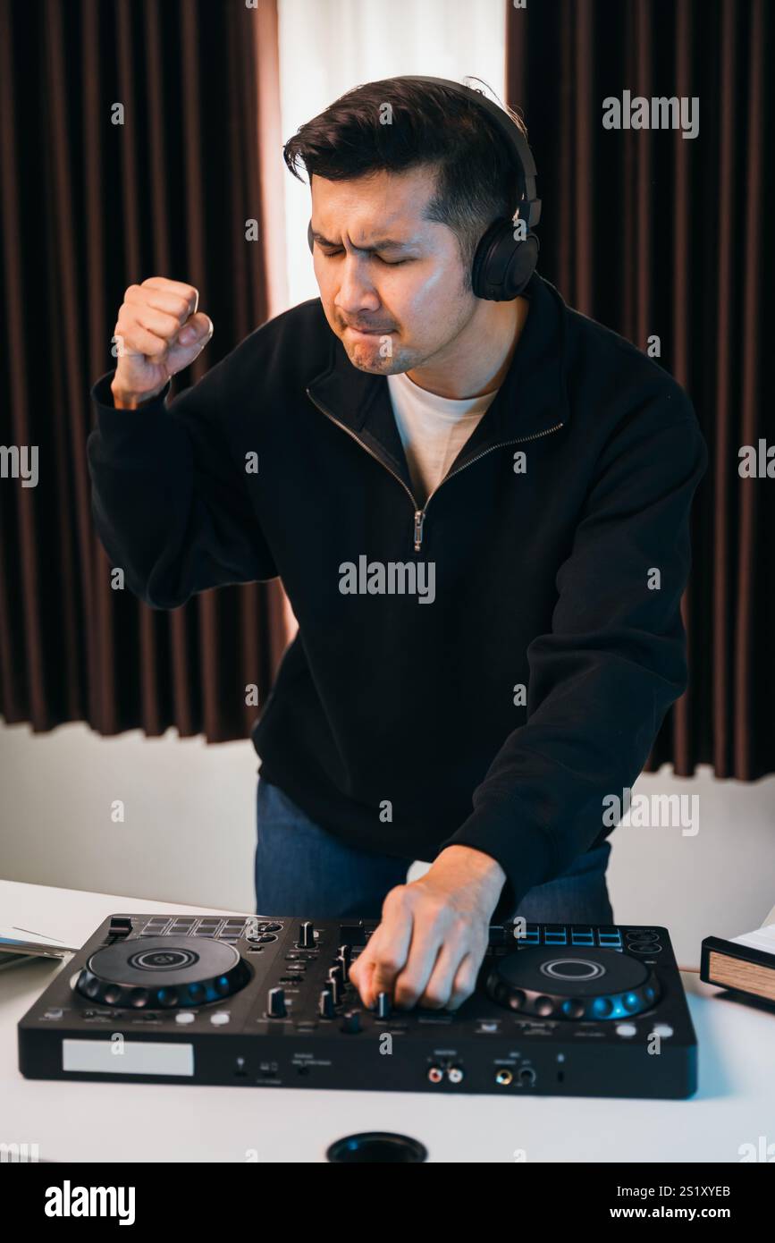 Un'elegante configurazione home disco con DJ che mixa brani su una console mixer compatta, luce ambiente calda e vibrazioni accoglienti. Foto Stock