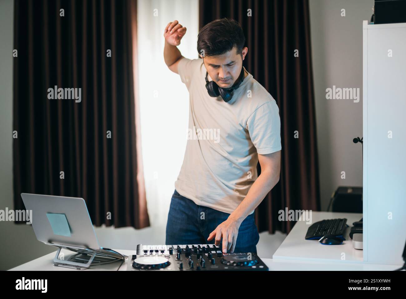 DJ home party che gira brani su una console mixer portatile. Foto Stock