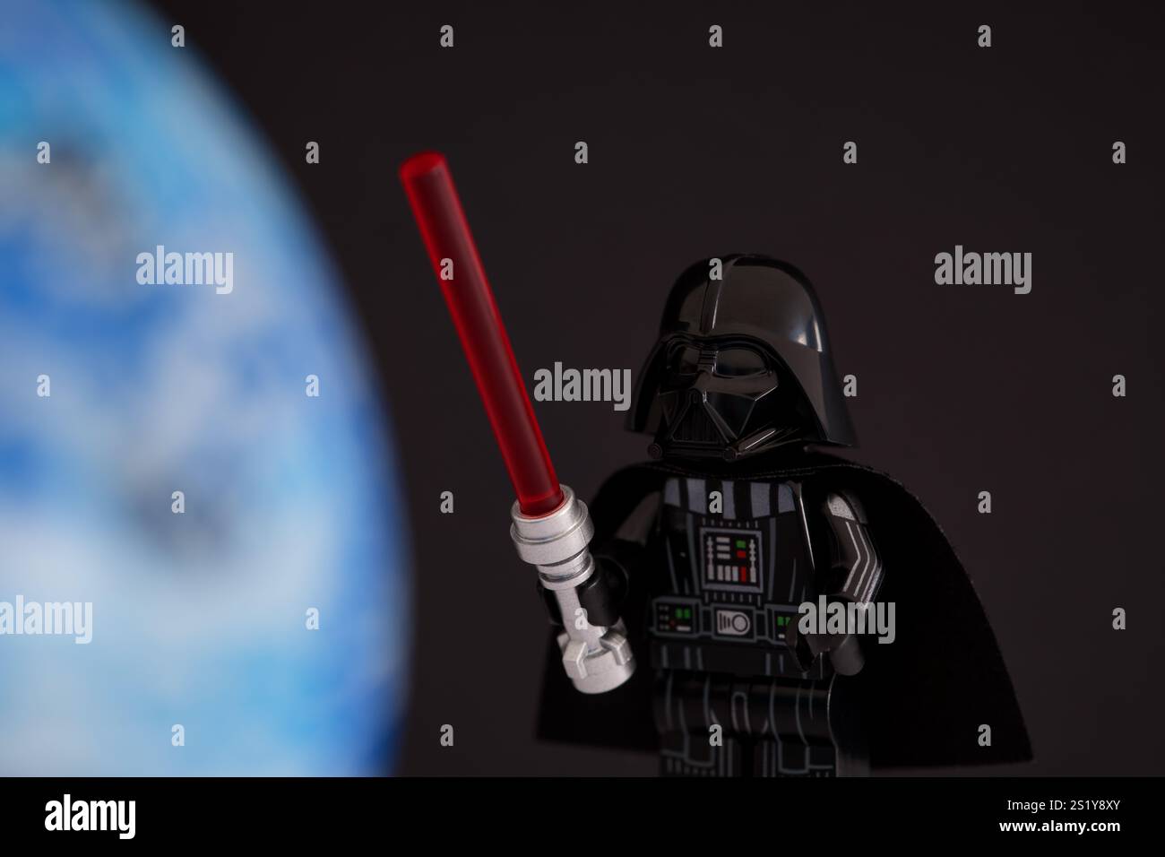 Tambov, Federazione Russa - 14 novembre 2024 Lego Darth Fener minifigure con spada laser rossa su sfondo nero con pianeta blu Foto Stock
