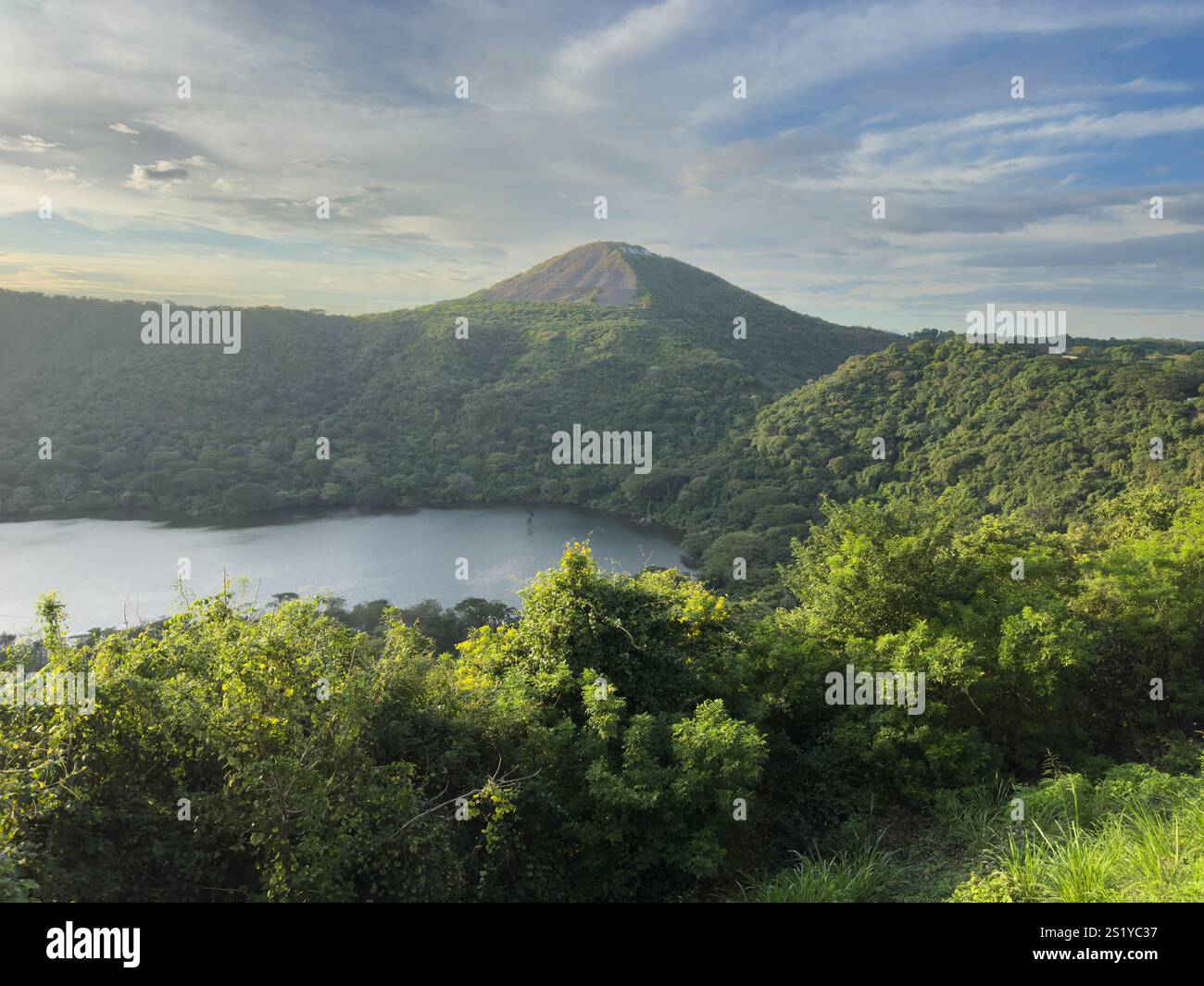 Splendida vista del vulcano dormiente circondato da fitti alberi e dal lago tranquillo durante l'ora d'oro. Foto Stock
