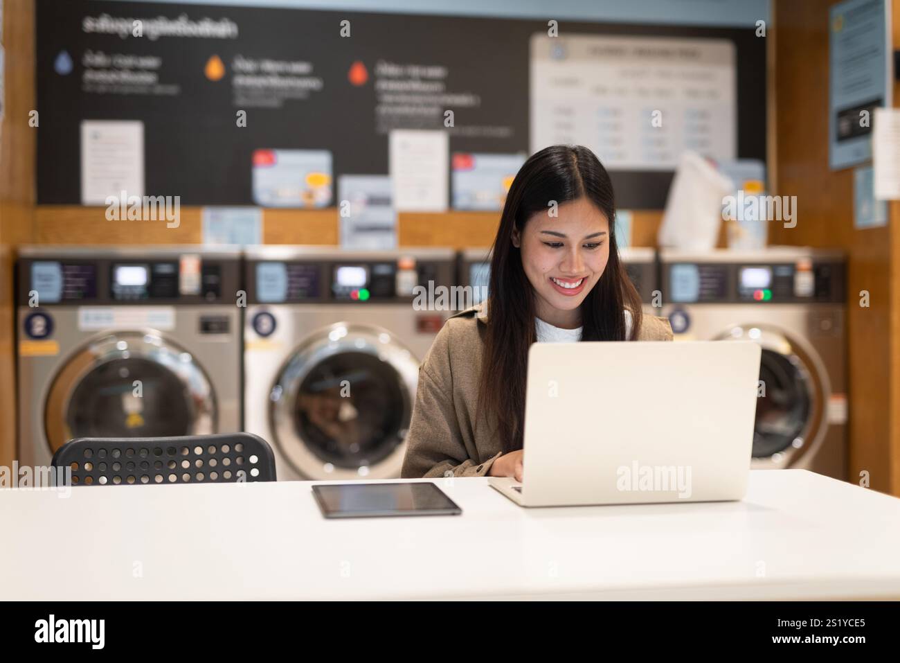 Donna che lavora su un notebook in un negozio di lavanderia Foto Stock