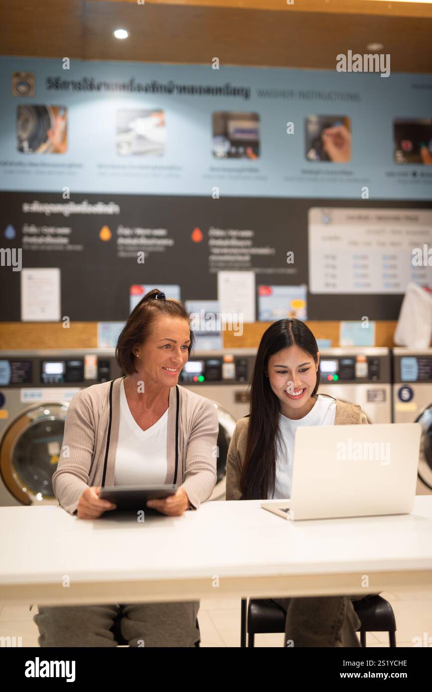 Due donne che lavorano su un computer in un negozio di lavanderia Foto Stock