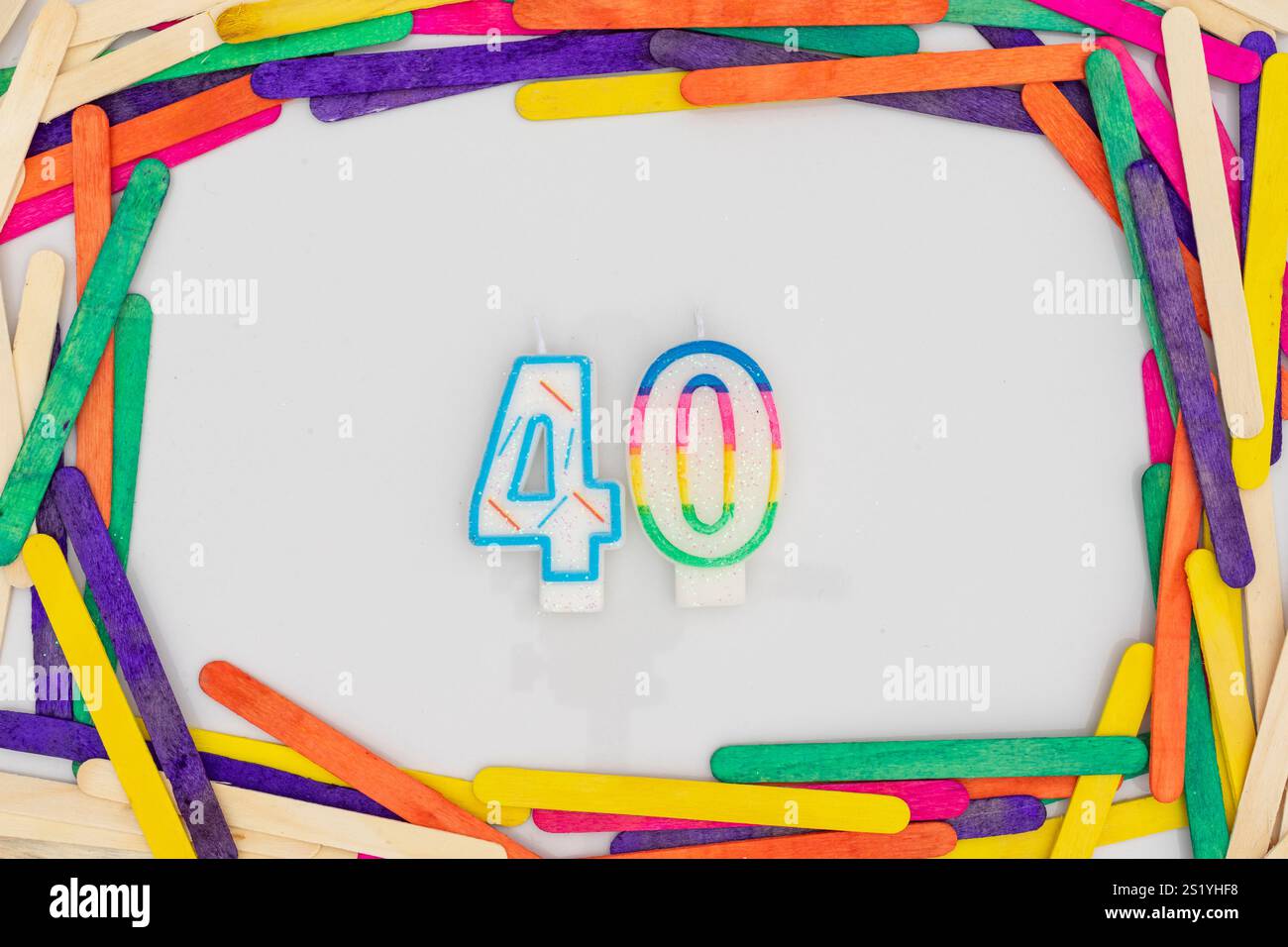 Le candele di compleanno a forma di 40 con bastoncini colorati incorniciano il bordo su sfondo bianco Foto Stock