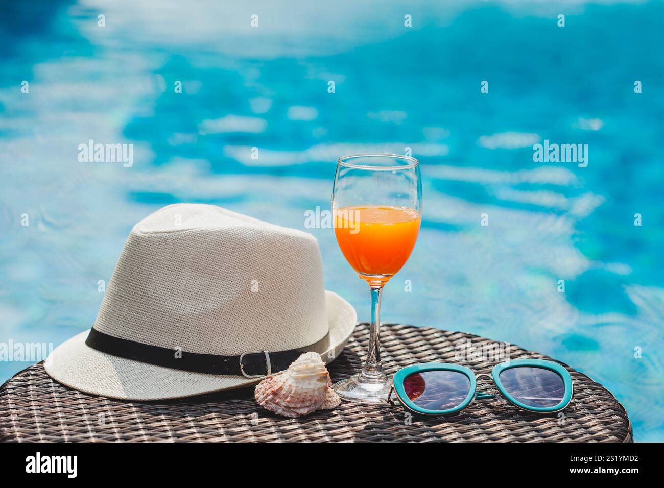 Vibrazioni estive a bordo piscina, occhiali da sole, cappello da spiaggia, succo rinfrescante, acqua limpida, relax, prendere il sole, vivere l'atmosfera tropicale e trascorrere momenti sotto il sole. Foto Stock