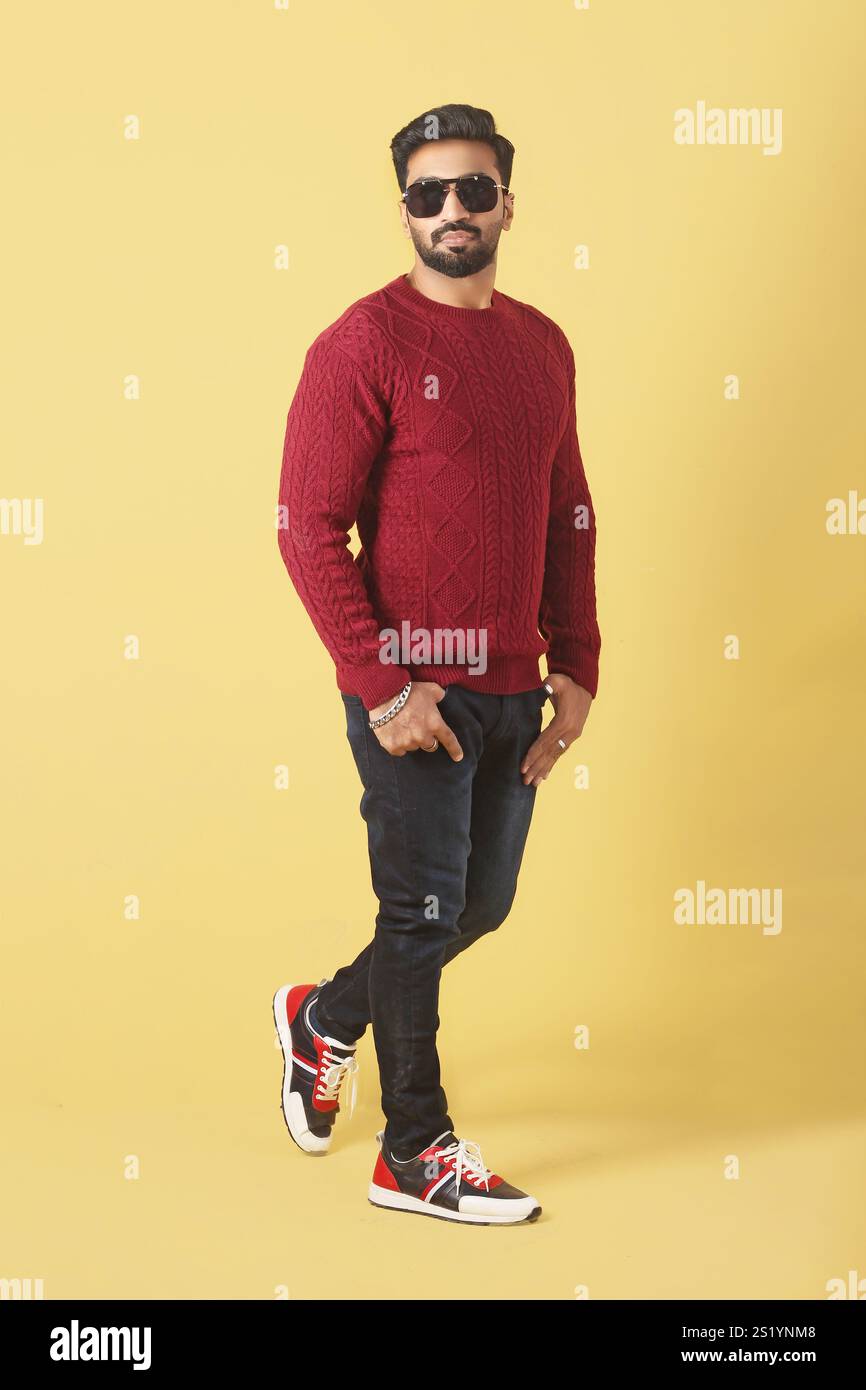 Un modello maschile asiatico che si posa in maglione rosso su sfondo giallo in stile Foto Stock