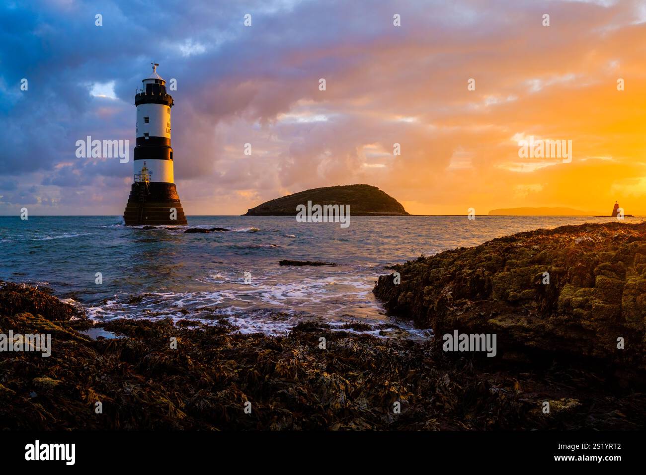 Alba al faro di Penmon (faro di Trwyn Du), Puffin Island (Ynys Seiriol) e Perch Rock Beacon, Penmon Point ad Anglesey, Galles del Nord Foto Stock