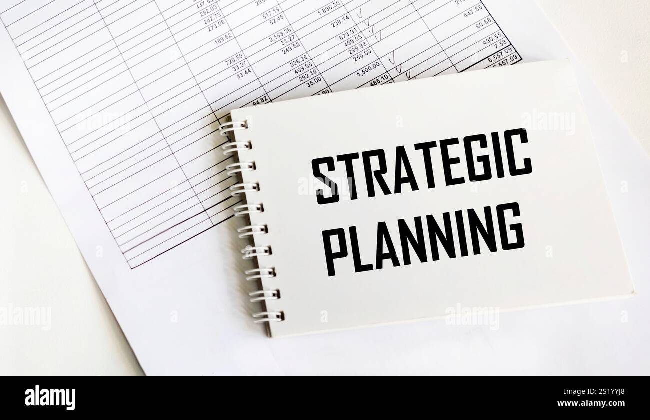 Un notebook etichettato come "PIANIFICAZIONE STRATEGICA" sui documenti finanziari Foto Stock