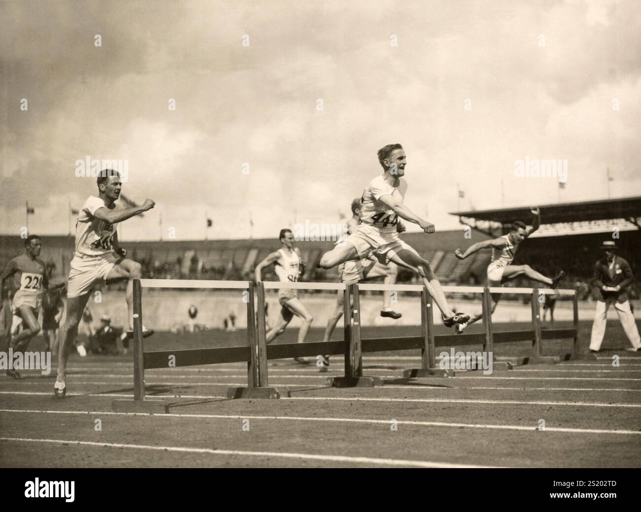1928 Giochi Olimpici di Amsterdam. Ultimi 400 metri ostacoli. L'inglese Lord David George Burghley (numero 444) sulla strada per l'oro allo Stadio Olimpico. Da sinistra a destra: Facelli ( 226, Italia), sesto posto; Livingston Learmonth (468, Inghilterra) quinto posto; Petterson (Svezia) quarto; Lord Burghley (444, Inghilterra), il vincitore finale; dietro Burghley Talor (USA) che arrivò terzo; di estrema destra Cushel (USA) che arrivò secondo. Paesi Bassi, Amsterdam, 1928. Foto Stock