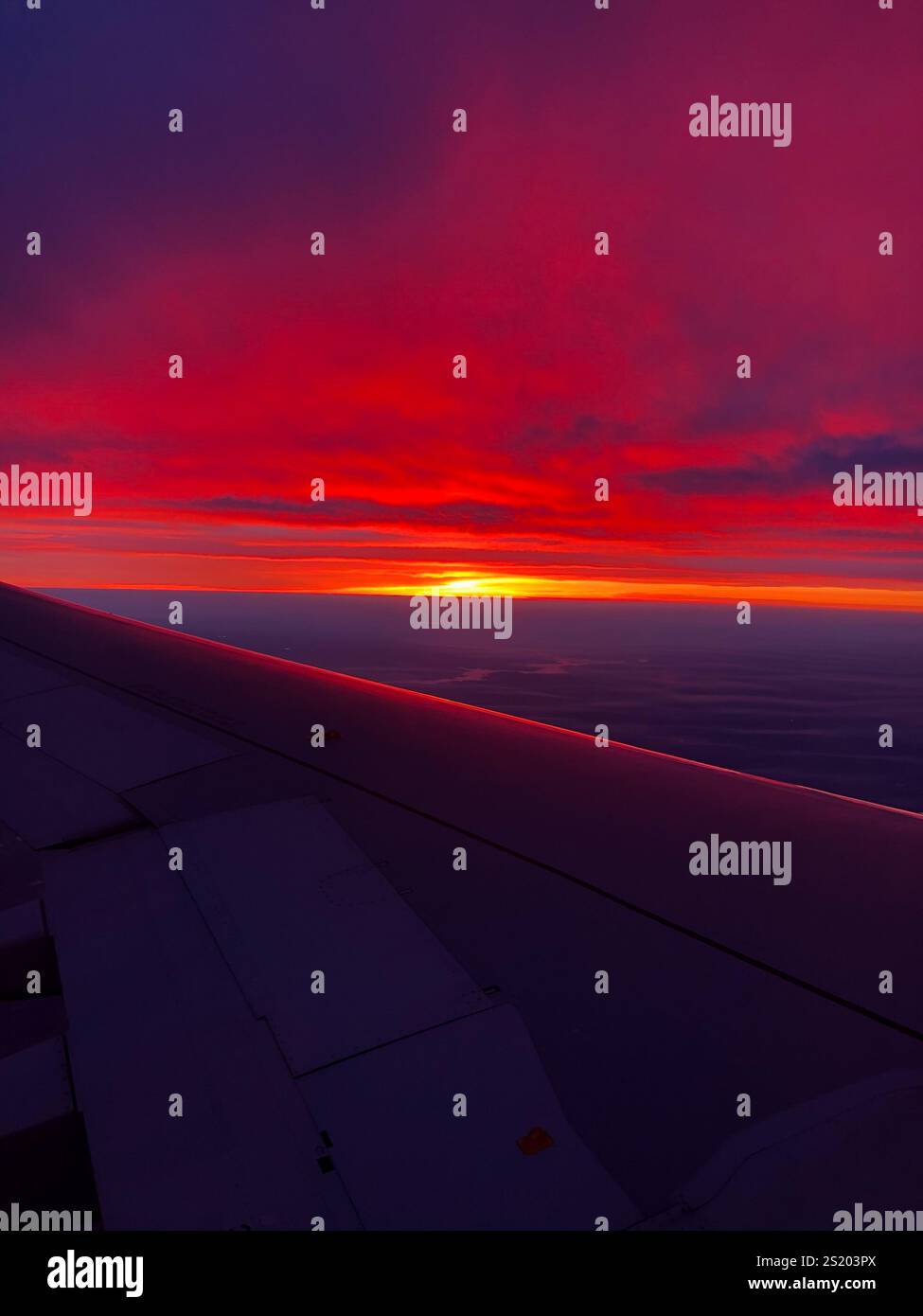 Bellissimo tramonto arancione e rosso viola dalla finestra dell'aereo - Immagine stock catturata con smartphone