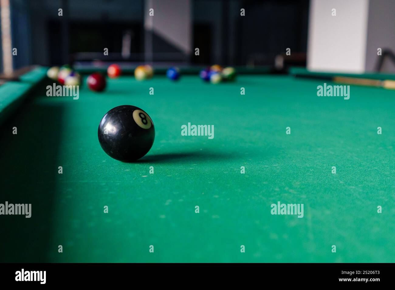 Un primo piano di un tavolo da biliardo che mette in evidenza una palla da otto a fuoco. Mostra la configurazione del gioco con palline colorate in attesa di giocare. Foto Stock