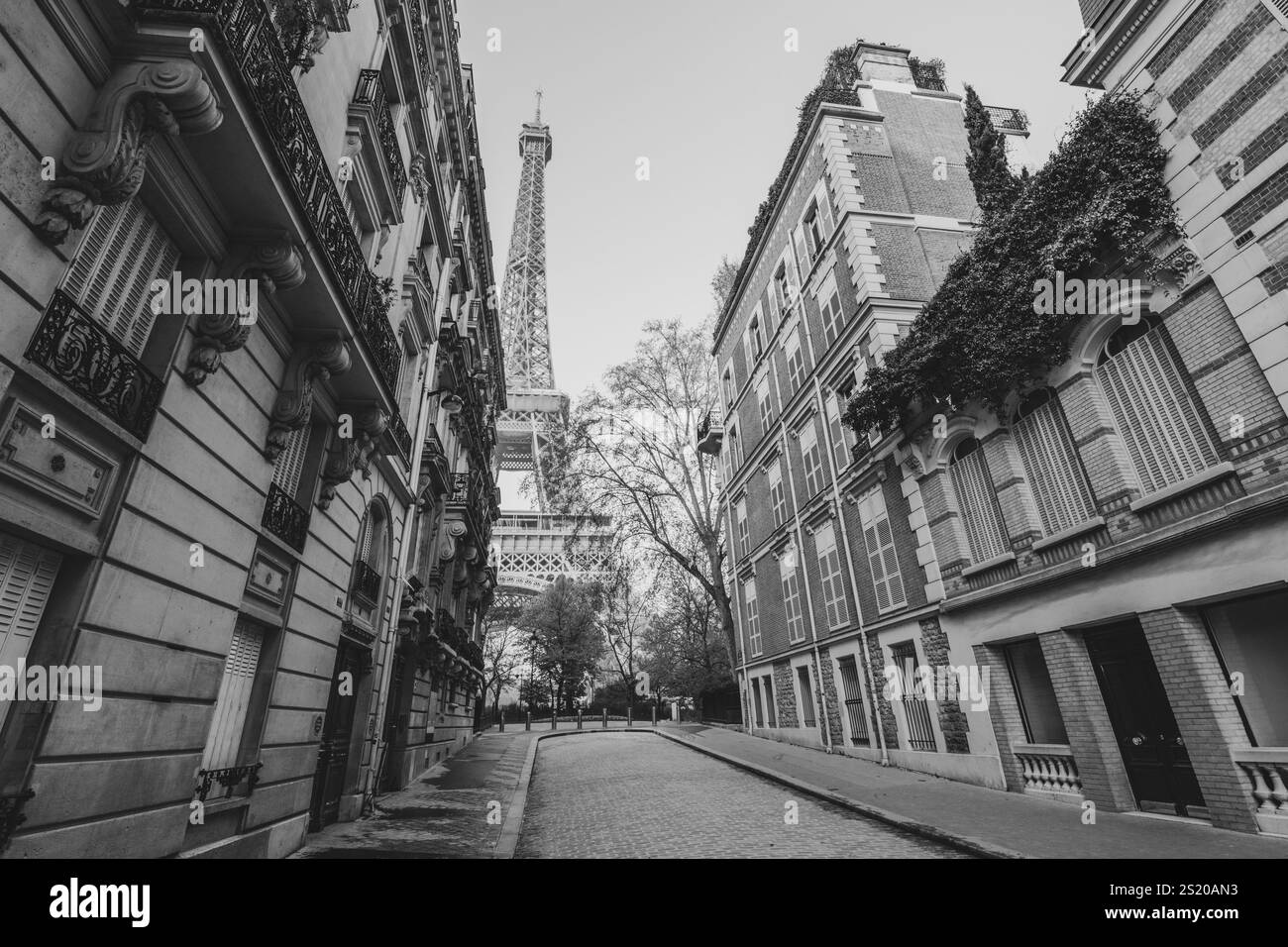 Una tranquilla mattinata a Parigi rivela un'affascinante strada incorniciata da eleganti edifici, con l'iconica Torre Eiffel che si erge tra di loro. L'atmosfera tranquilla invita a esplorare la zona. Foto Stock