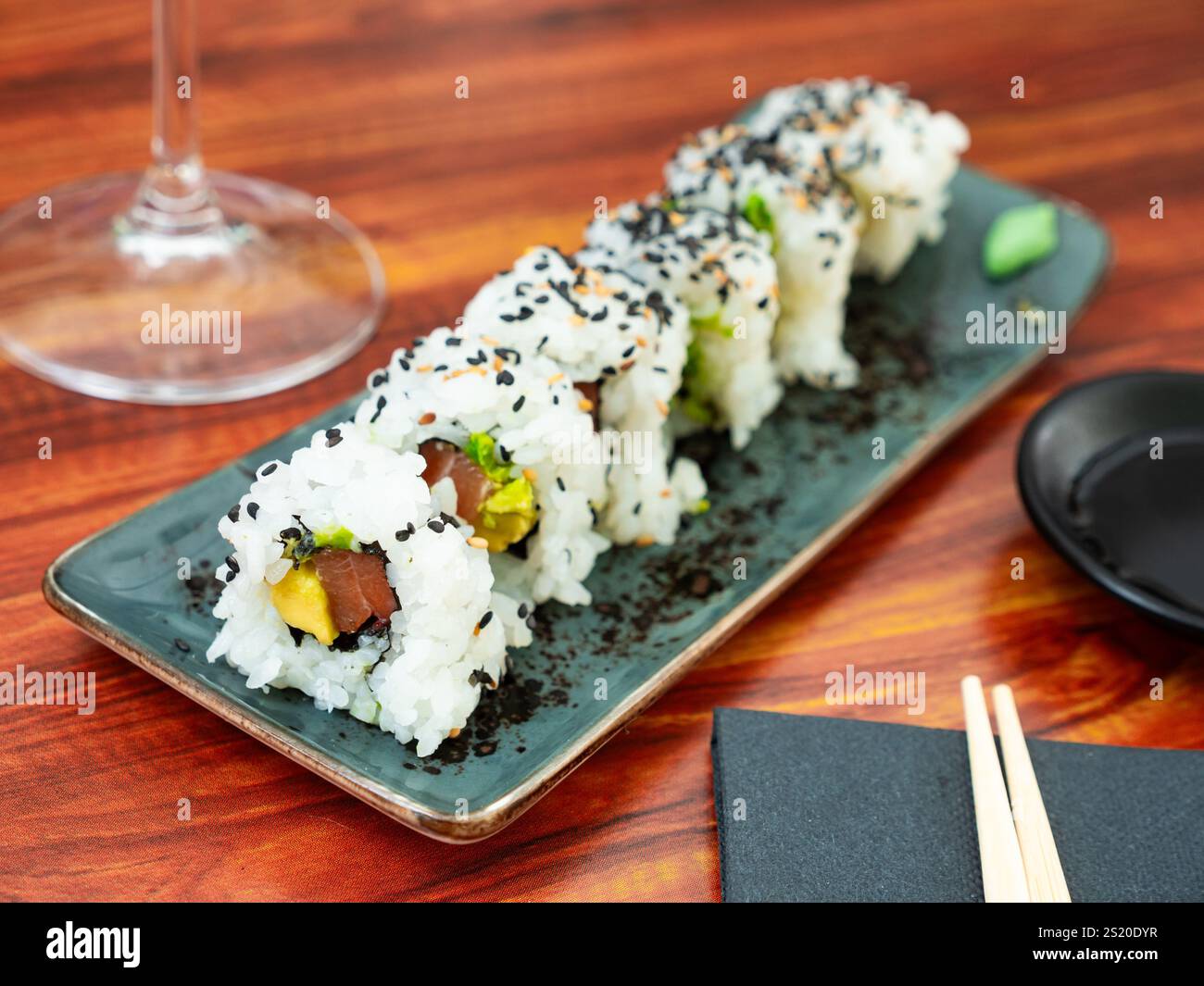 Set di panini sushi freschi con salmone, avocado e semi di sesamo serviti sul piatto. Foto Stock