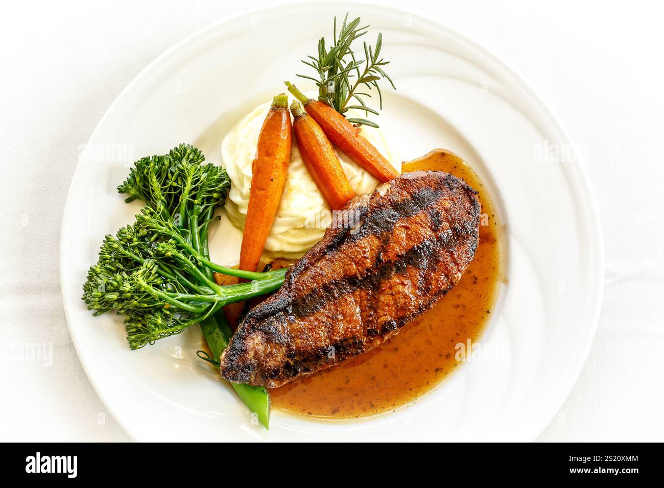 Un piatto di cibo con bistecca, carote e broccoli. I broccoli si trovano sul lato sinistro del piatto e le carote sul lato destro Foto Stock