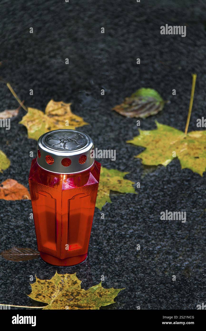 Una tomba di luce per il giorno di Ognissanti in autunno con foglie Foto Stock