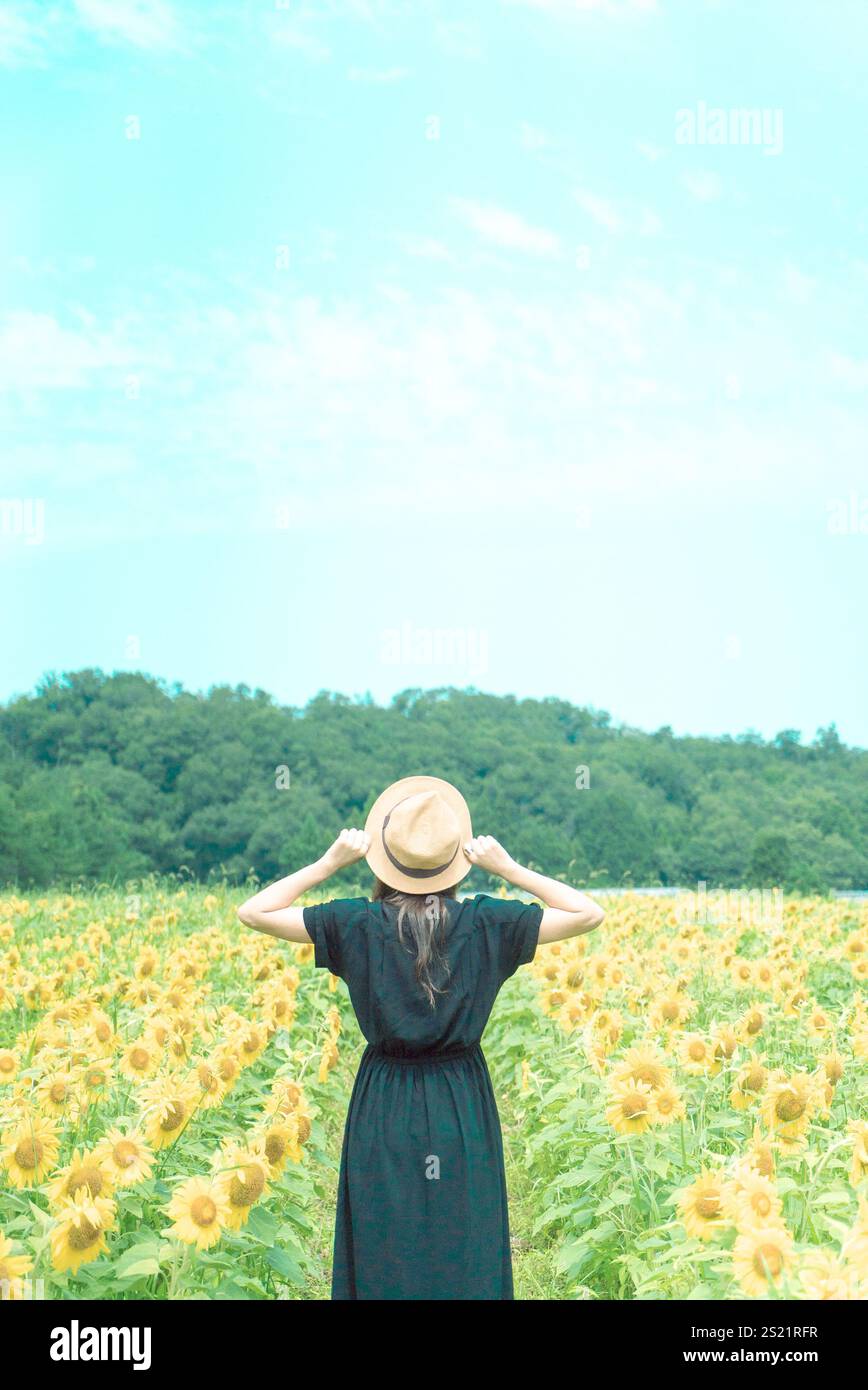 Donna che guarda indietro nel campo di girasole Foto Stock