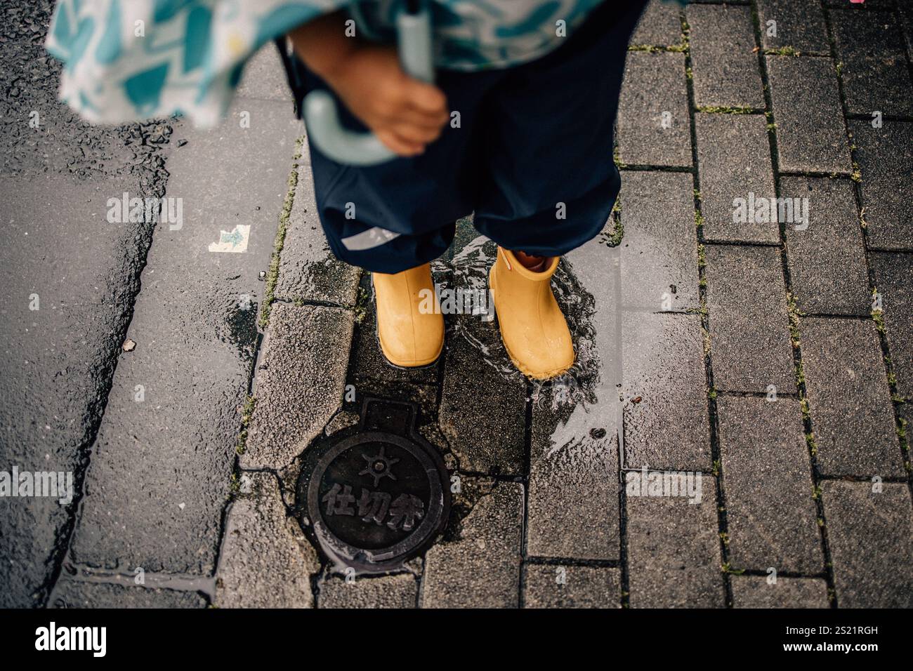 Bambino che indossa stivali gialli Foto Stock