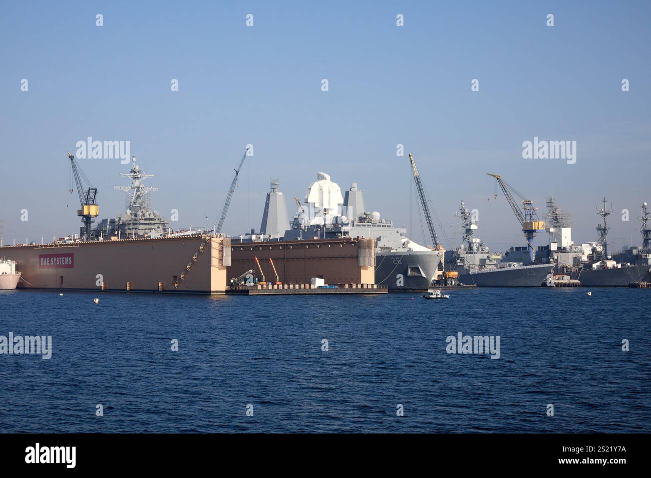 San Diego, California, Stati Uniti. 21 dicembre 2024. Una vista panoramica del vivace cantiere navale di San Diego, California, che mette in risalto le operazioni di bacino di carenaggio. Il bacino di carenaggio, visibile in primo piano, ospita la USS Halsey (DDG-97), un cacciatorpediniere missilistico guidato classe Arleigh Burke, in fase di manutenzione. Intorno al bacino di carenaggio si trovano gru e altre navi navali, che mostrano il cuore operativo del cantiere. Una barca a vela solitaria scivola attraverso le acque calme, contrastando l'ambiente industriale con la sua presenza serena. (Credit Image: © Ian L. Sitren/ZUMA Press Wire) SOLO PER USO EDITORIALE! Non per Co Foto Stock