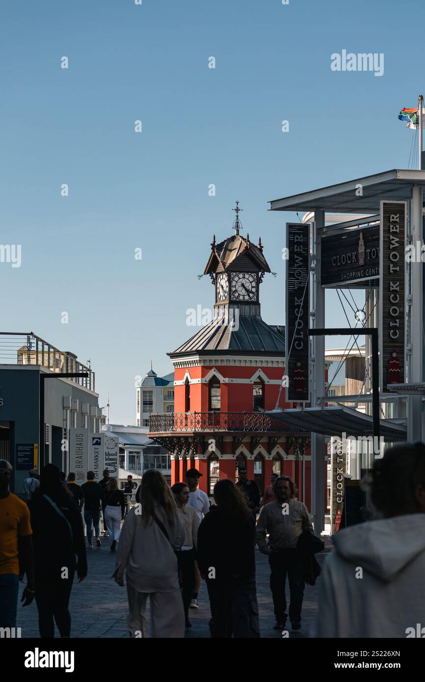 Le persone camminano vicino a un monumento storico della città, il lungomare della Torre dell'Orologio. La strada serale prima del tramonto è piena di turisti. Città del Capo, Sou Foto Stock