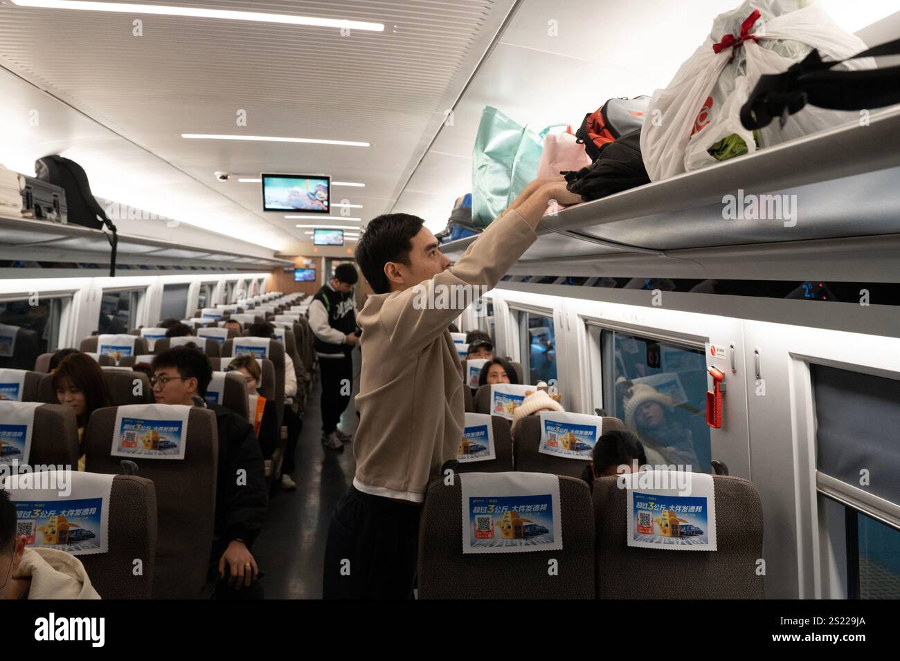 Hangzhou, Cina. 5 gennaio 2025. I passeggeri depositano i loro bagagli sul portabagagli di un treno presso la stazione ferroviaria di Hangzhou Ovest il 5 gennaio 2025 a Hangzhou, nella provincia cinese di Zhejiang. Con il lancio dei servizi ferroviari ad alta velocità tra la stazione ferroviaria di Hangzhou West e Hong Kong West Kowloon, i passeggeri da Hangzhou possono ora raggiungere la loro destinazione - Hong Kong in un giorno. Credito: Wu Junyi/China News Service/Alamy Live News Foto Stock