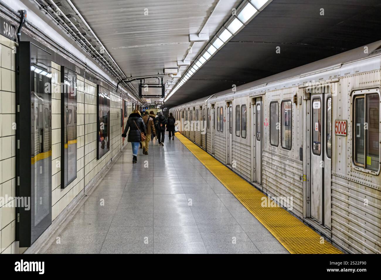 Persone che camminano sulla piattaforma di una stazione della metropolitana sulla linea 2 dove un vecchio treno è fermo Foto Stock
