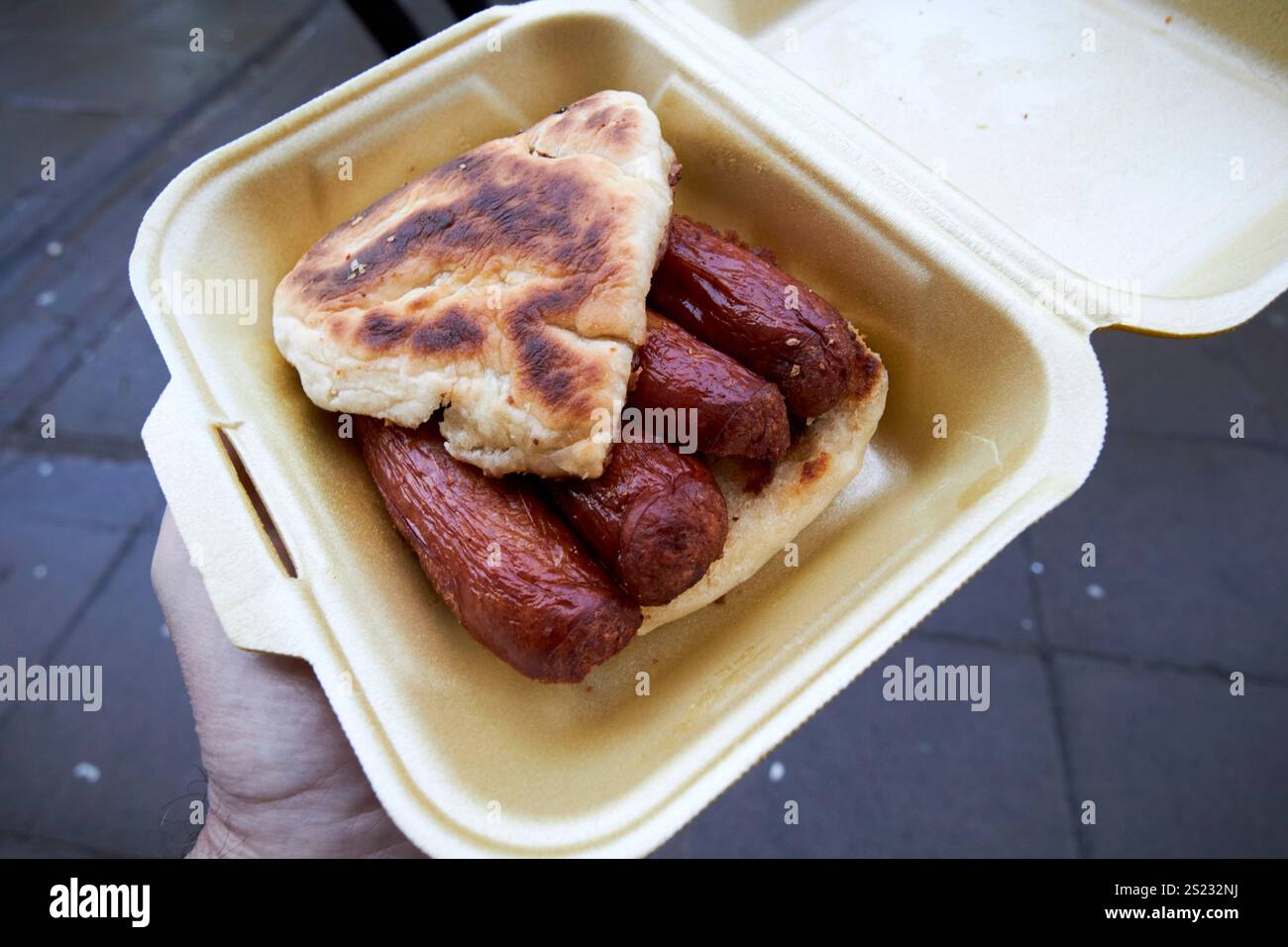 uomo che cammina in giro portando con sé una colazione con salsicce e bibita mentre vai belfast, irlanda del nord, regno unito Foto Stock
