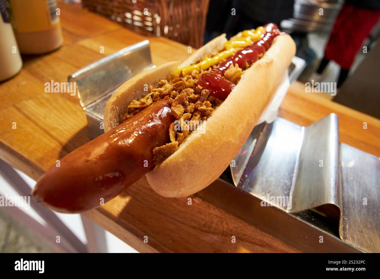 cipolle fritte senape e ketchup su un enorme hot dog frankfurter tedesco in un mercatino di natale a belfast, irlanda del nord, regno unito Foto Stock