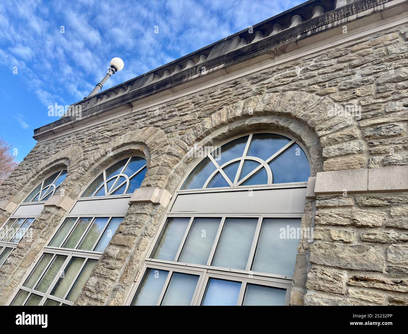 Facciata di edificio in pietra con finestre ad arco che riflettono il cielo blu Foto Stock Facciata di edificio in pietra con finestre ad arco che riflettono il cielo blu Foto Stock