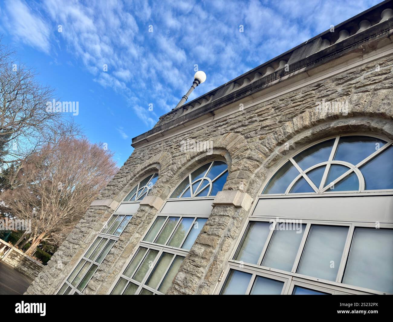 Elegante edificio in pietra con finestre ad arco e un cielo azzurro Foto Stock Elegante edificio in pietra con finestre ad arco e un cielo azzurro Foto Stock