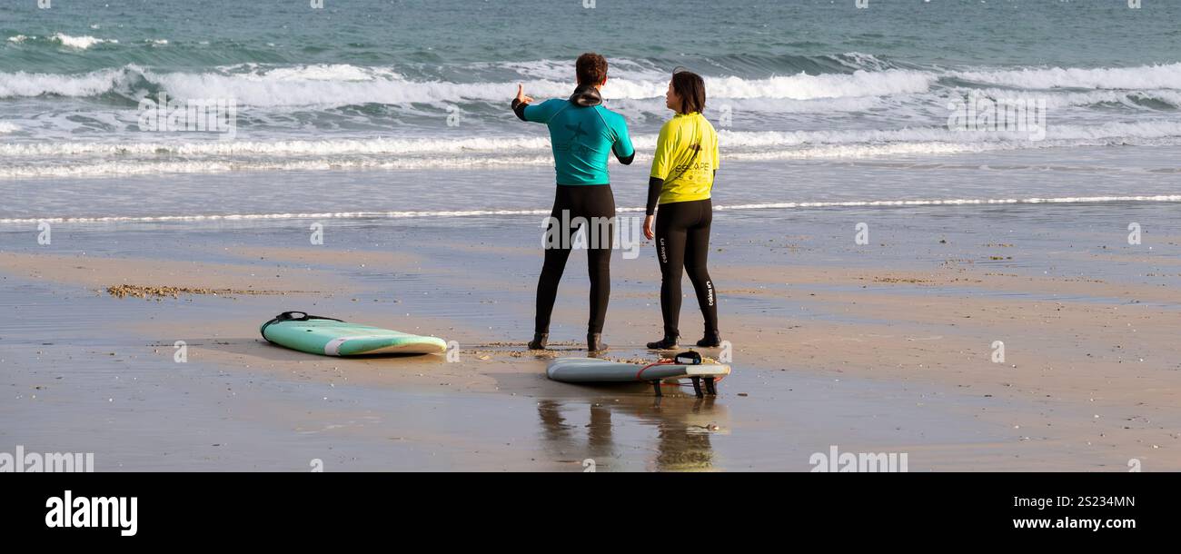 Un'immagine panoramica di un istruttore di surf della Escape Surfing School che tiene una lezione di surf uno a uno con un principiante a Towan Beach a Newquay Foto Stock