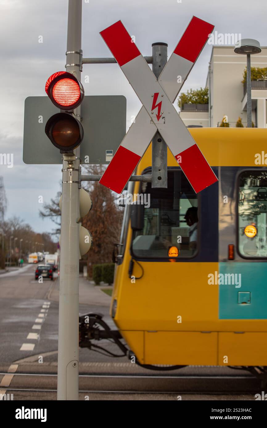 Treno tedesco Light Rail che attraversa una strada con semaforo rosso e segnale di attraversamento Foto Stock