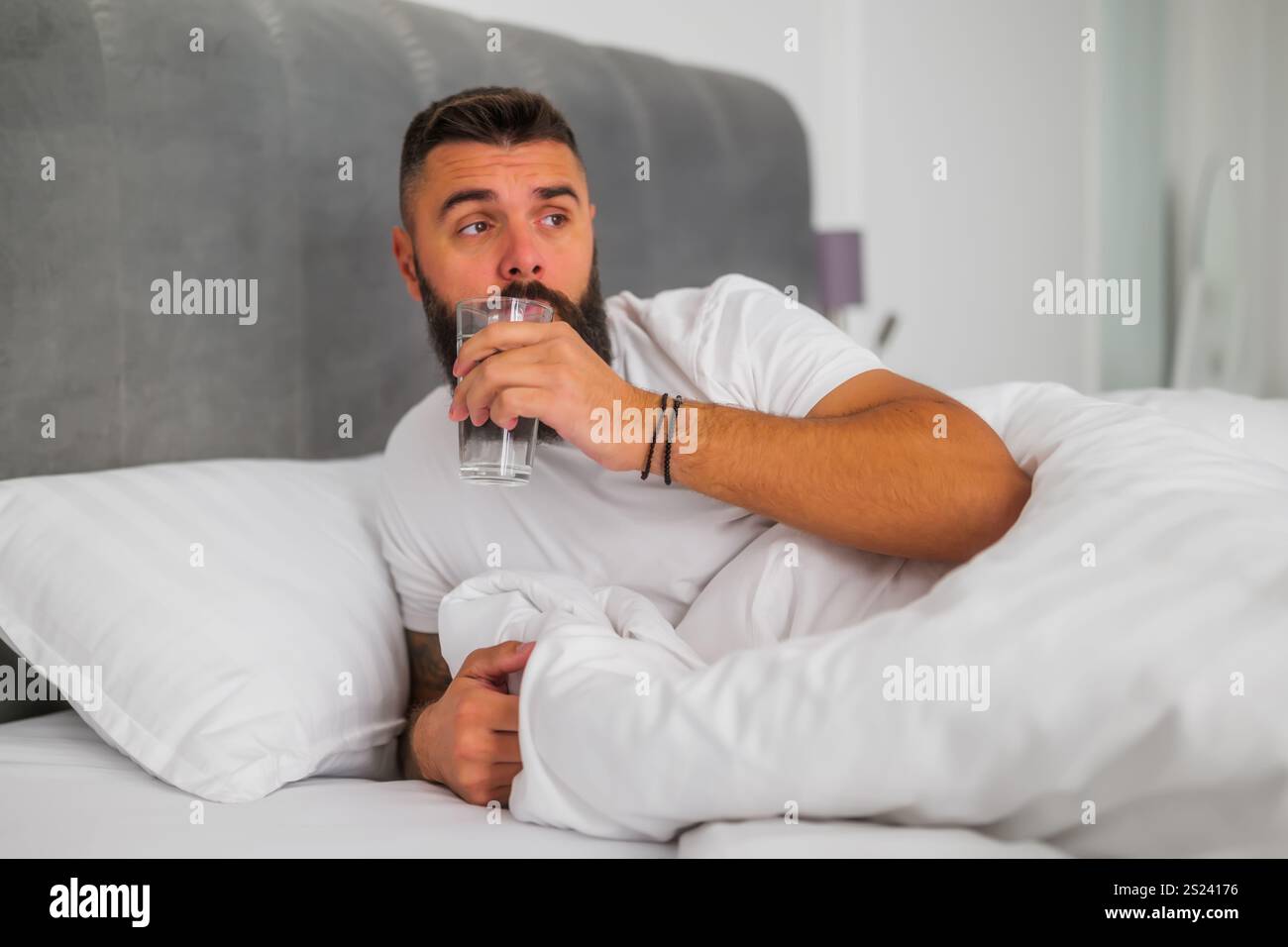 L'uomo si sveglia la mattina e beve acqua. Foto Stock