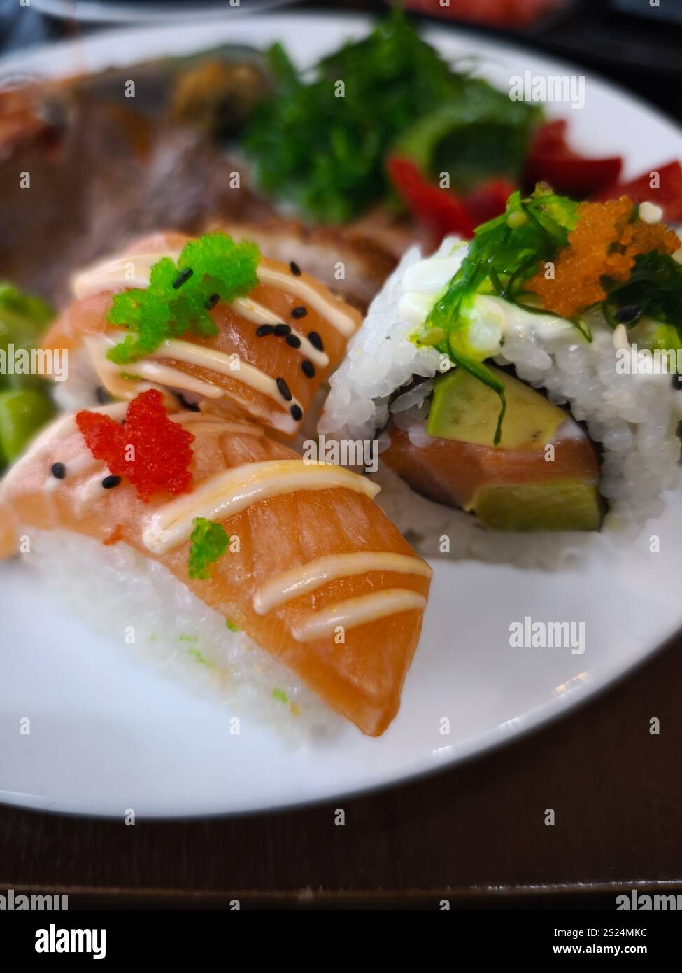 Sushi preparato al momento, con nigiri di salmone e maki Rolls, si siede invitantemente su un piatto bianco, mostrando colori vivaci e texture tutto quello che puoi fare Foto Stock