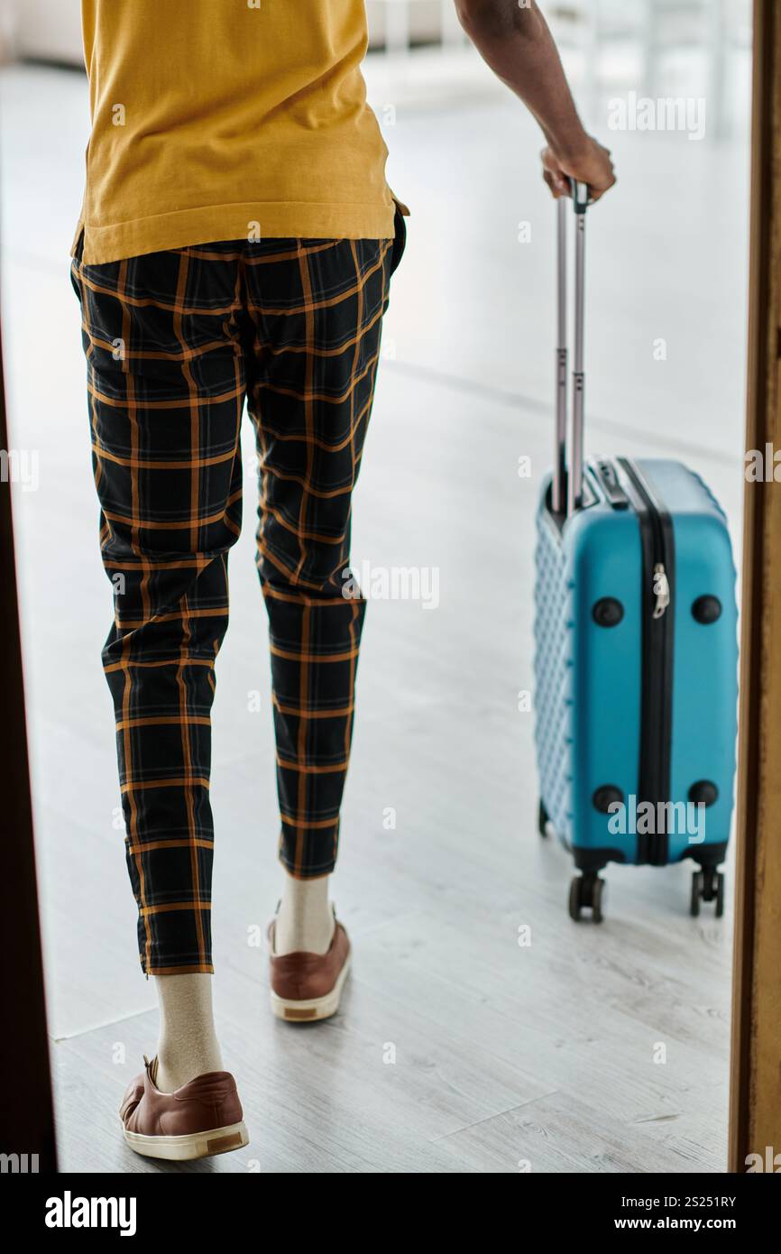 Un giovane afroamericano tira una valigia, pronto ad abbracciare il suo stile di vita da remoto. Foto Stock