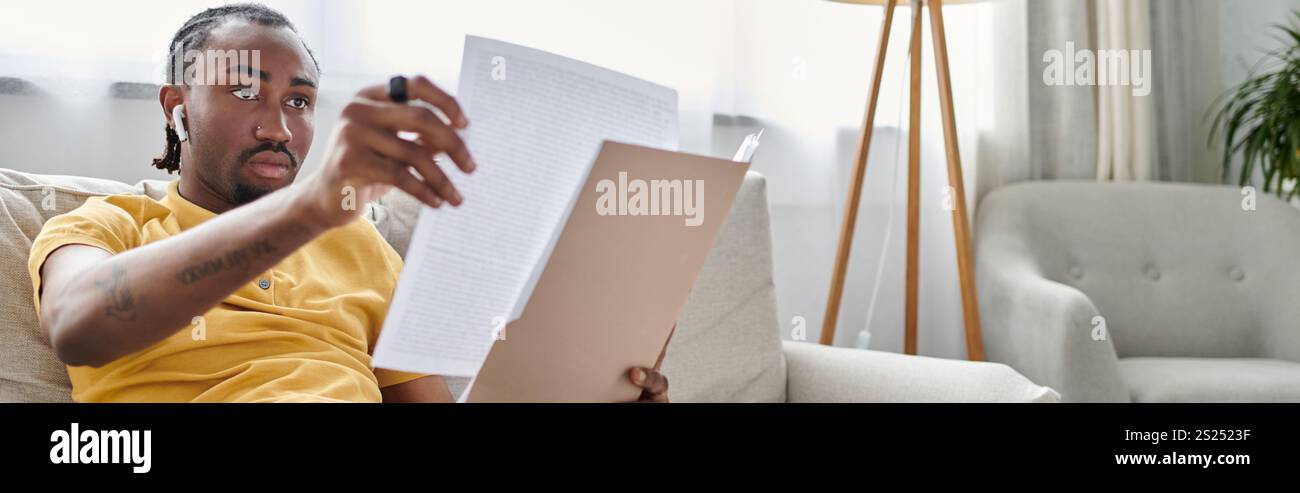 Persona concentrata che lavora in remoto mentre esamina documenti importanti in una stanza luminosa Foto Stock