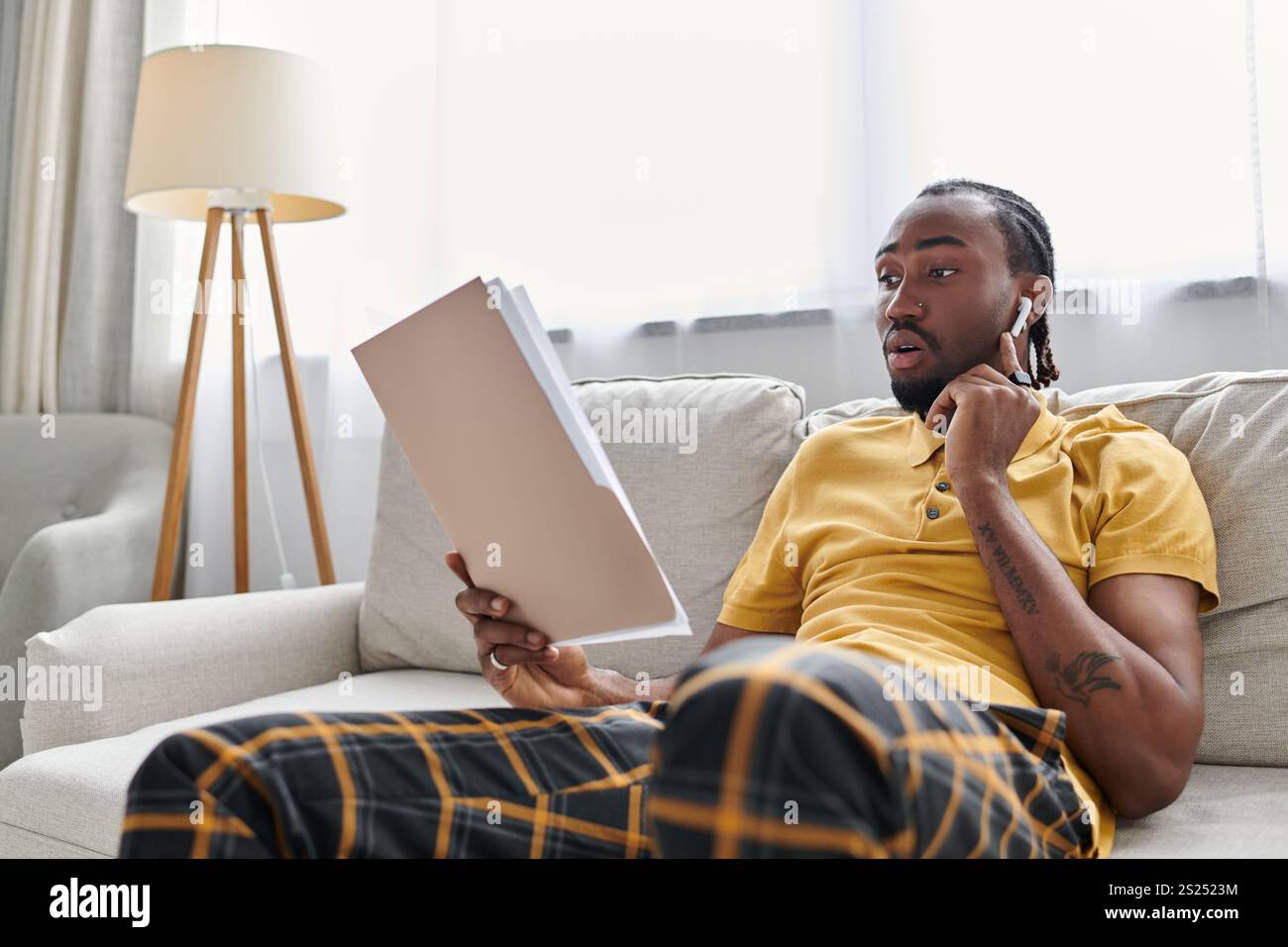 L'uomo afroamericano si impegna nello stile di vita dei nomadi digitali, rivedendo i documenti a casa. Foto Stock