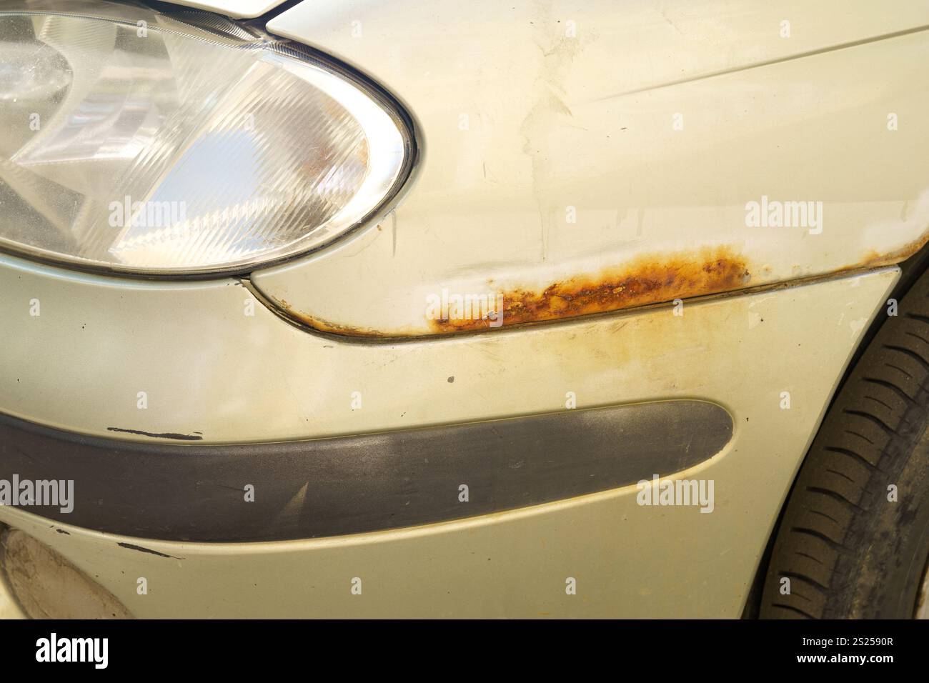 Un'auto trascurata mostra una notevole ruggine sulla carrozzeria, mostrando il decadimento di una vernice un tempo vivace. L'usura rivela il passare del tempo in un urba Foto Stock