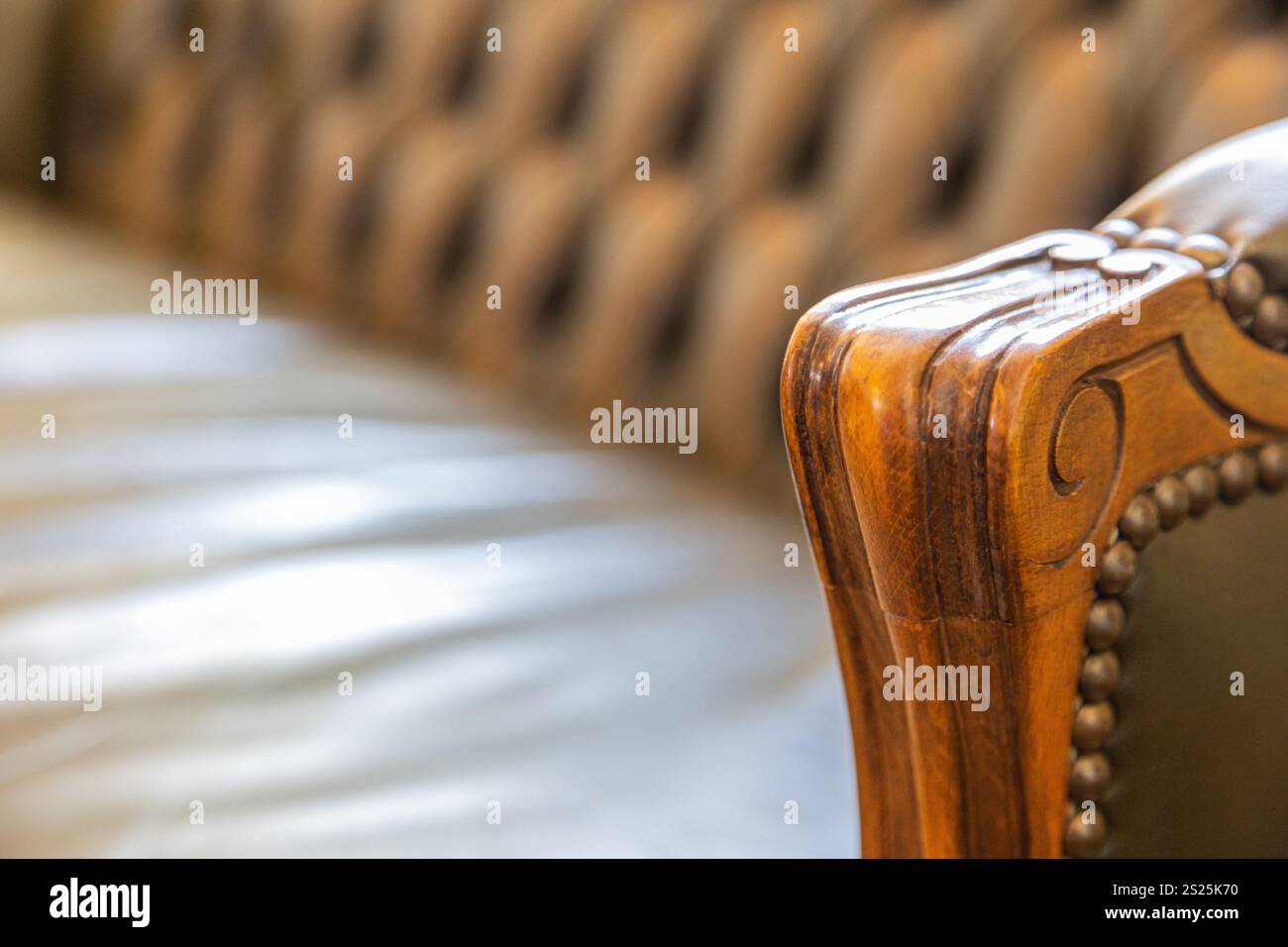 Una vista ravvicinata di un'elegante sedia in pelle verde che presenta un bracciolo in legno dal design splendido. La sedia è collocata in un ambiente interno ben illuminato Foto Stock