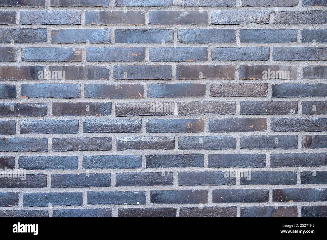 Una parete di mattoni blu-grigi mostra un motivo testurizzato con varie sfumature, creando un interessante effetto visivo ideale per l'ispirazione del design o. Foto Stock