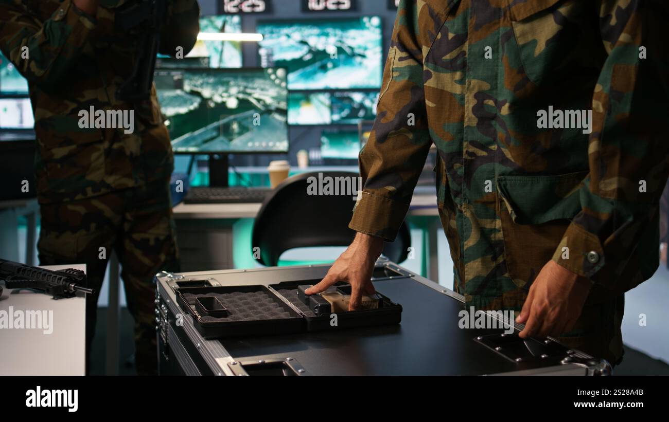 Ufficiale militare che controlla le pistole nella sala di comando, per assicurarsi che i proiettili e le forniture funzionino correttamente. Primo piano di un soldato che tiene in mano la pistola, gestisce le attrezzature di carico da combattimento, telecamera B. Foto Stock