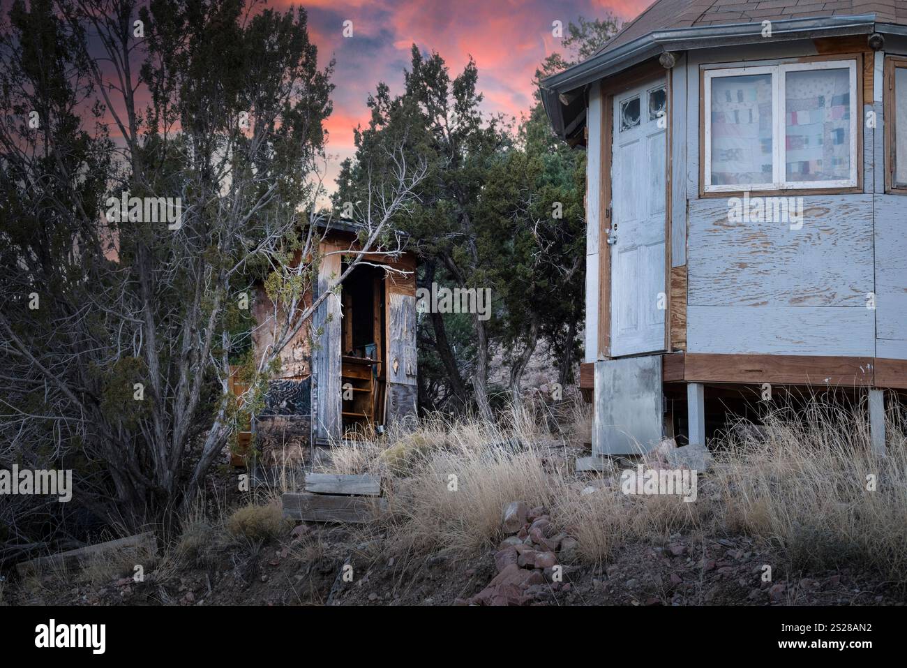 Una struttura simile a una yurta realizzata con pannelli di legno blu con tetto in tegole e un'attico con uno sfondo di vibranti tramonti mentre si vive fuori dalla griglia a Norther Foto Stock