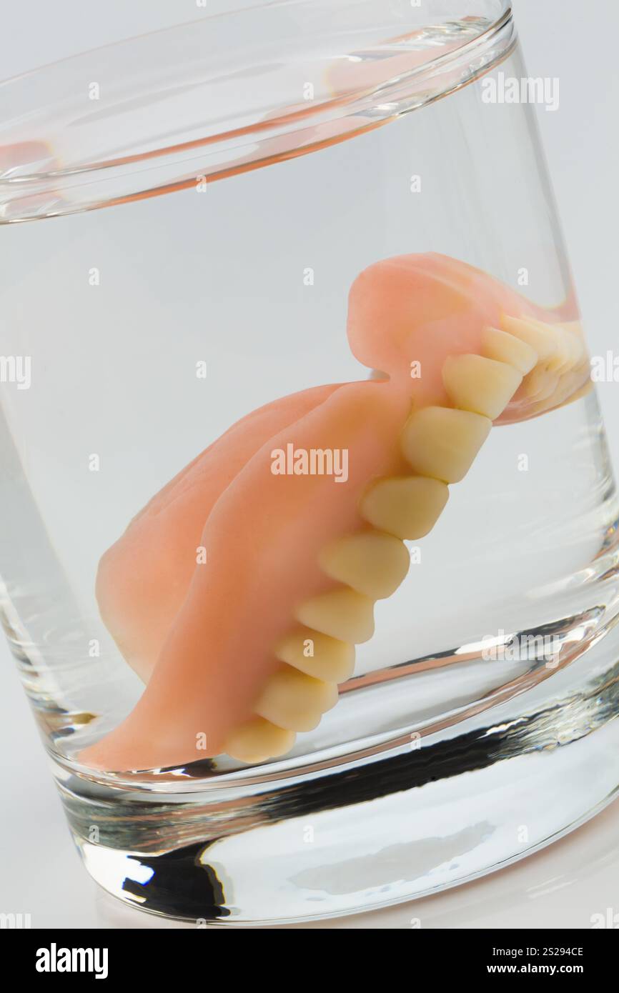 Dentatura con vetro d'acqua, foto simbolica per protesi e cura Foto Stock