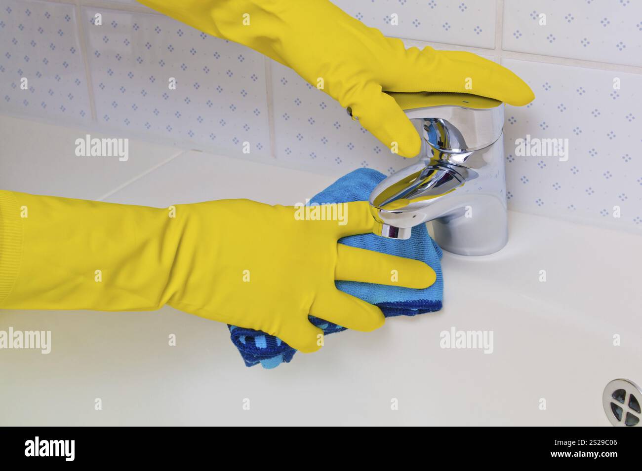 Il lavandino di un bagno viene pulito con guanti in lattice. Austria Foto Stock