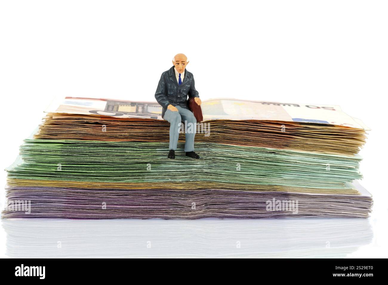 Foto simbolica per il pensionamento e la sicurezza vecchiaia, figura di un vecchio seduto su una pila di banconote Austria Foto Stock