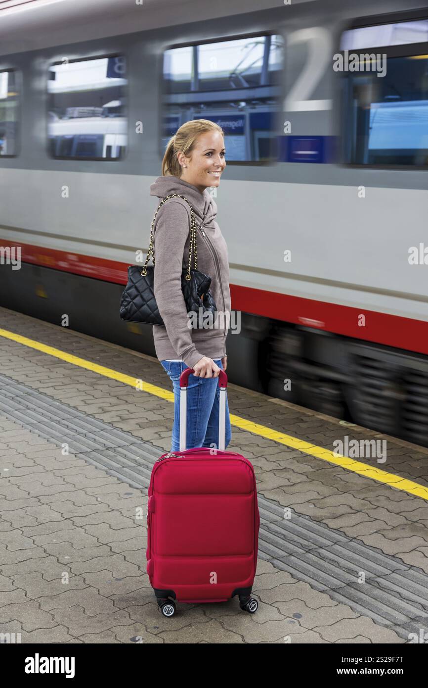 Una giovane donna aspetta un treno in una stazione ferroviaria. Viaggio in treno in vacanza in Austria Foto Stock