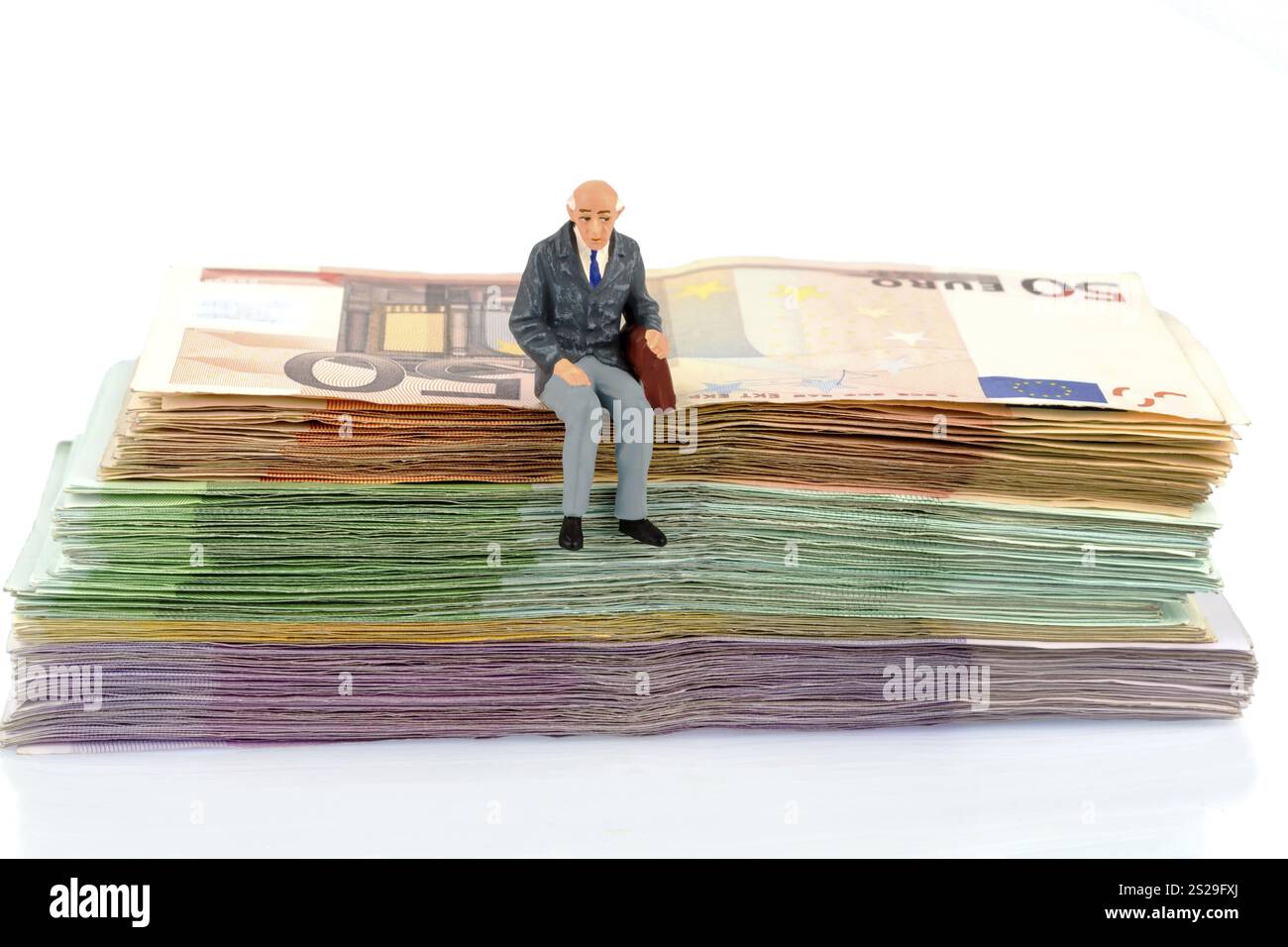 Foto simbolica per il pensionamento e la sicurezza vecchiaia, figura di un vecchio seduto su una pila di banconote Austria Foto Stock