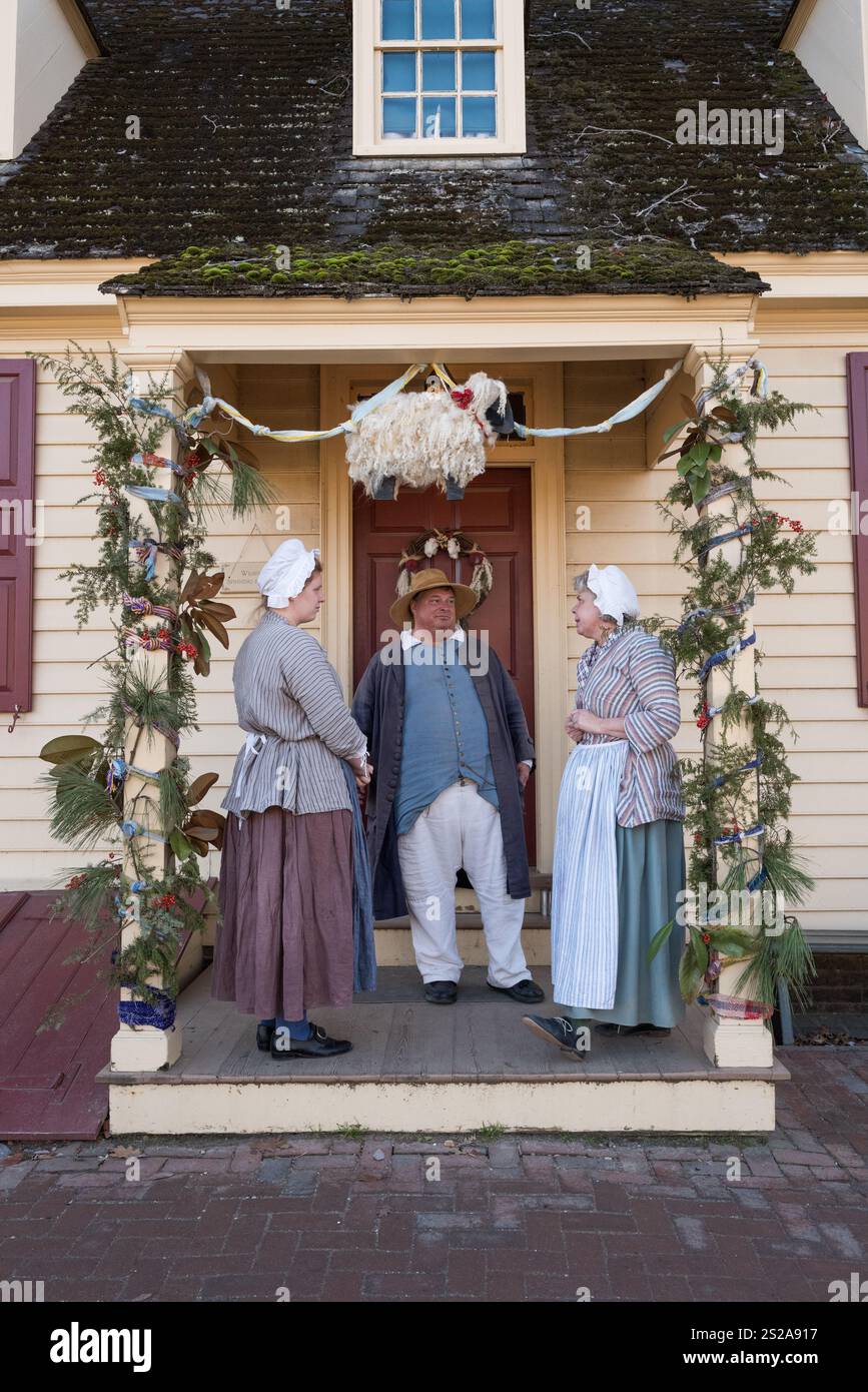 Williamsburg, Virginia USA - 18 dicembre 2017: Un uomo e due donne in abito d'epoca chiacchierano in una casa decorata per le vacanze nella città coloniale di Williamsburg. Foto Stock