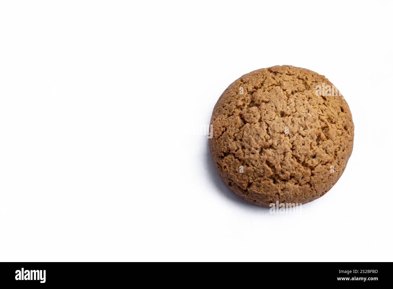Un unico biscotto rotondo di farina d'avena collocato su un pulito sfondo bianco, che mostra la sua consistenza marrone-oro e il fascino rustico Foto Stock