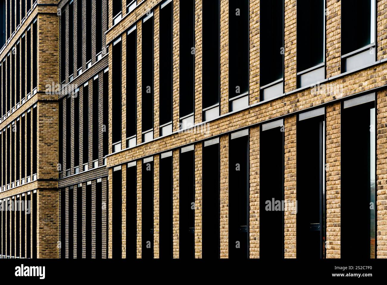 Facciata in mattoni con finestre verticali ripetitive e design architettonico simmetrico Foto Stock