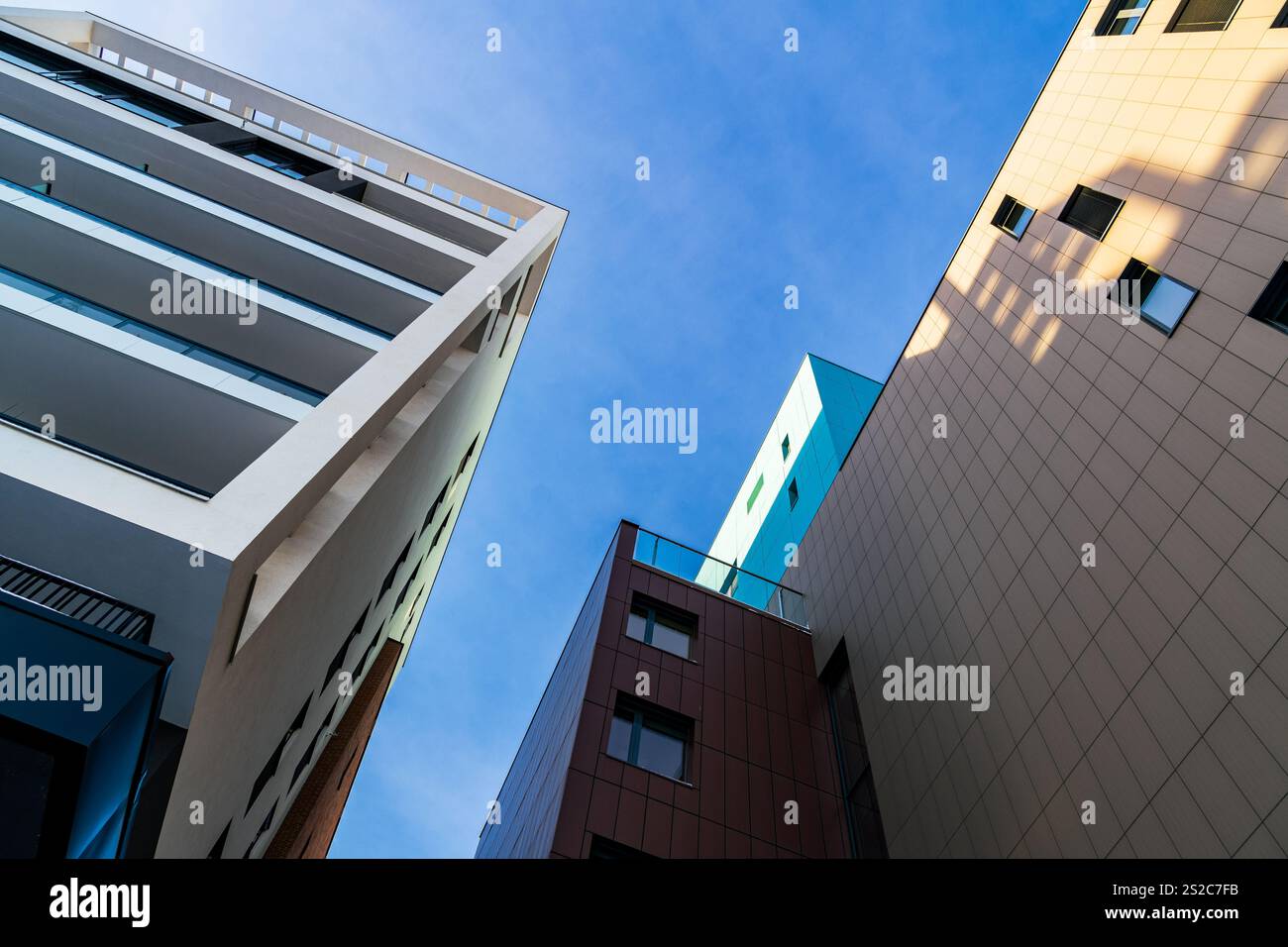 Moderno edificio residenziale a più piani con facciata vivace, grandi balconi e skyline urbano sotto il cielo azzurro Foto Stock